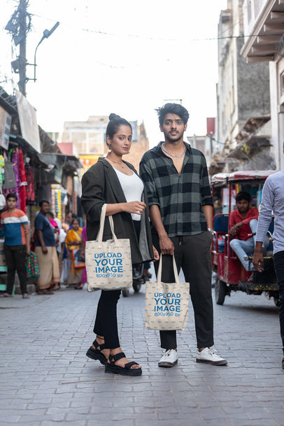 Mockup of a Couple Holding Tote Bags on The Street