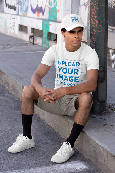 T-Shirt Mockup Featuring a Young Man Wearing a Dad Hat in an Urban Setting