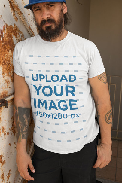 T-Shirt Mockup Featuring a Bearded Man Leaning Against a Rusty Wall