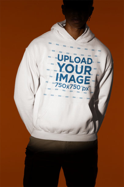 Gildan Mockup Featuring a Man Wearing a Pullover Hoodie While Posing Under a Spotlight