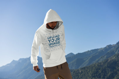 Mockup of a Man Wearing a Hoodie with Mountains in the Background